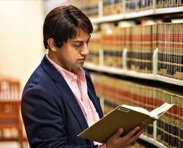 A law student reviews a book in the library.