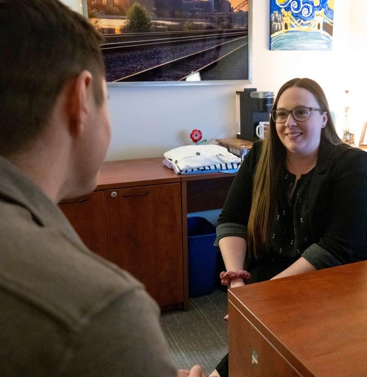 An advisor sitting at a desk works with a student.